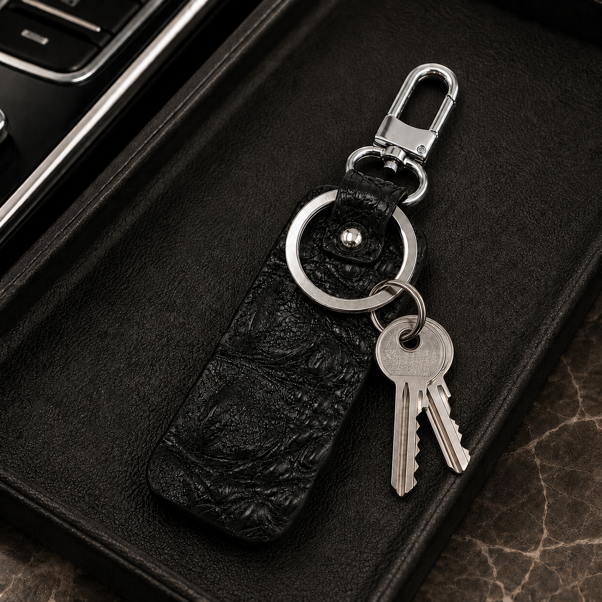 Black Kensington alligator leather key fob with two silver keys attached to the large key ring on a luxury leather surface.