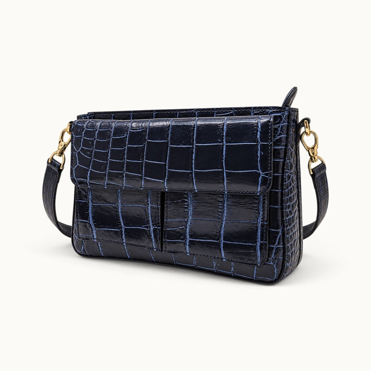 Three-quarter view of navy crocodile bag with detachable short crocodile strap and gold hardware
