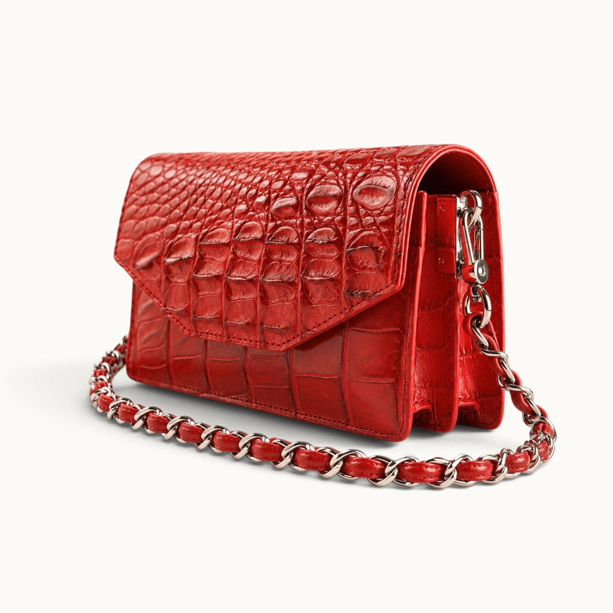 Angled front view of The Chelsea red Siamese crocodile leather shoulder bag showing its structured silhouette and braided chain strap.