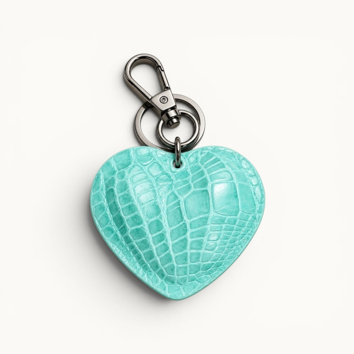 The Heart Key Charm in turquoise Siamese crocodile leather with a heart-shaped silhouette, polished silver-tone clasp, and keyring.