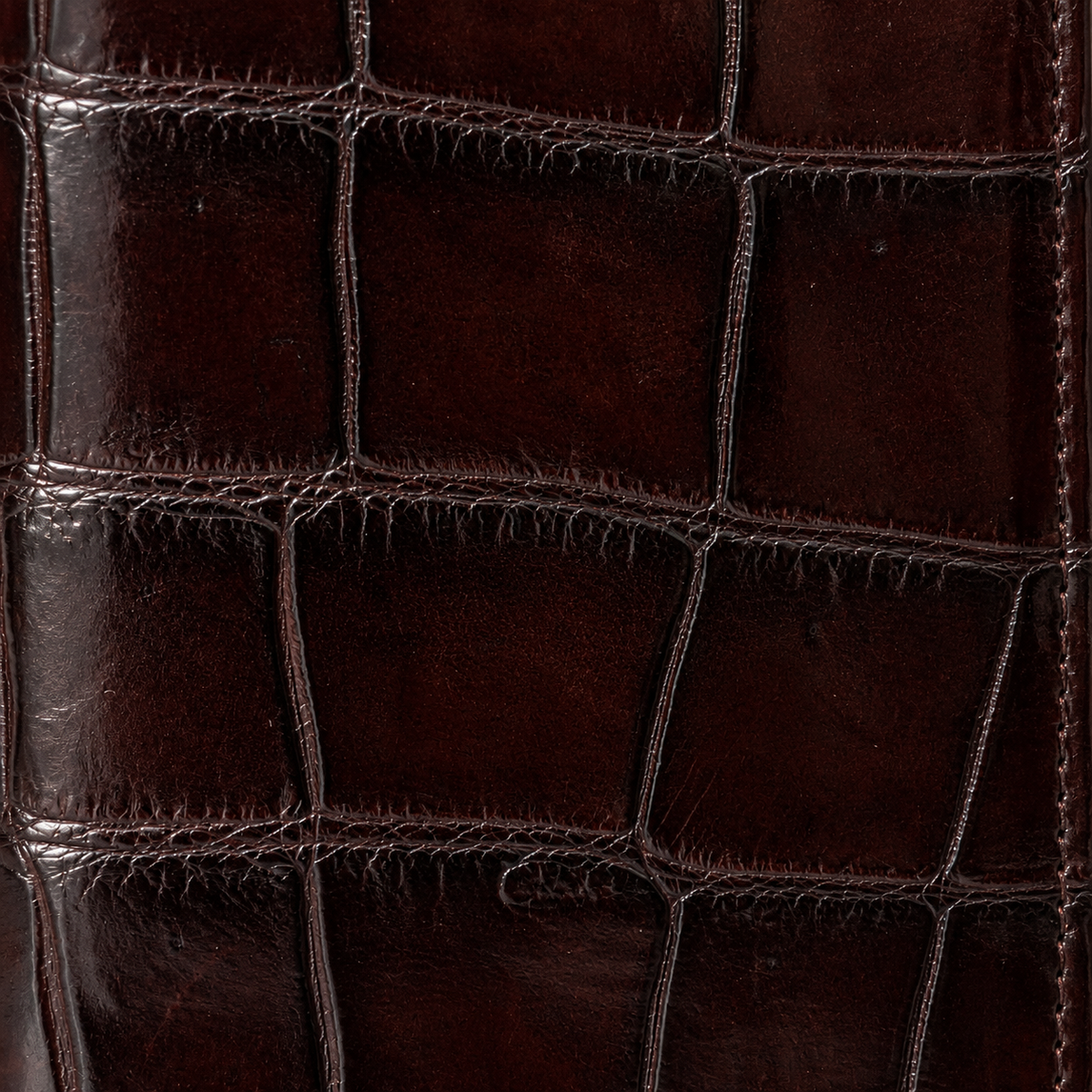 Detailed texture close-up of genuine crocodile leather on The Kingsley Long Wallet in Imperial Mahogany featuring natural scales and rich hand-polished finish.