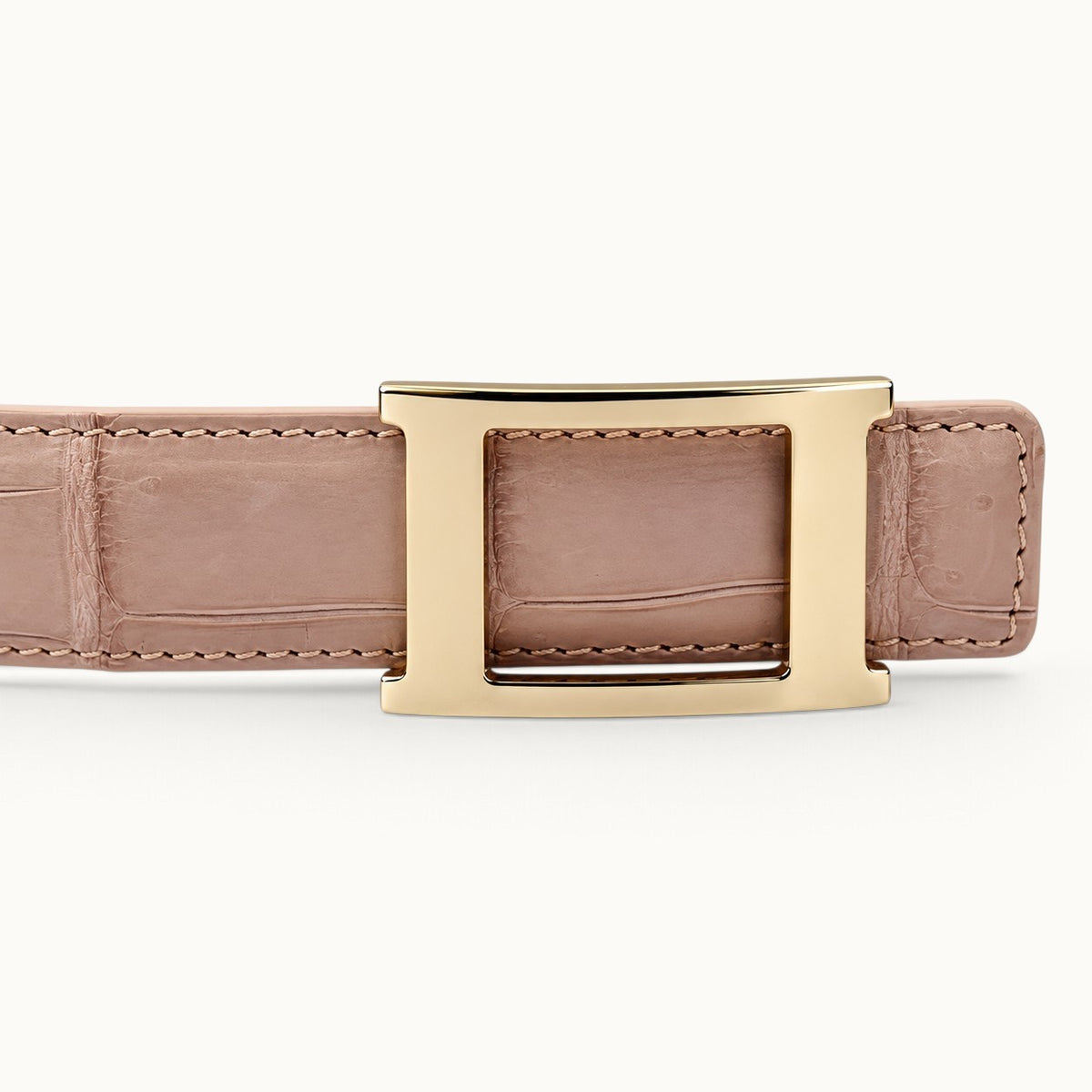Close-up of The Rosalie Crocodile Belt featuring a geometric gold-tone stainless steel buckle, blush pink crocodile leather, and matching stitching.