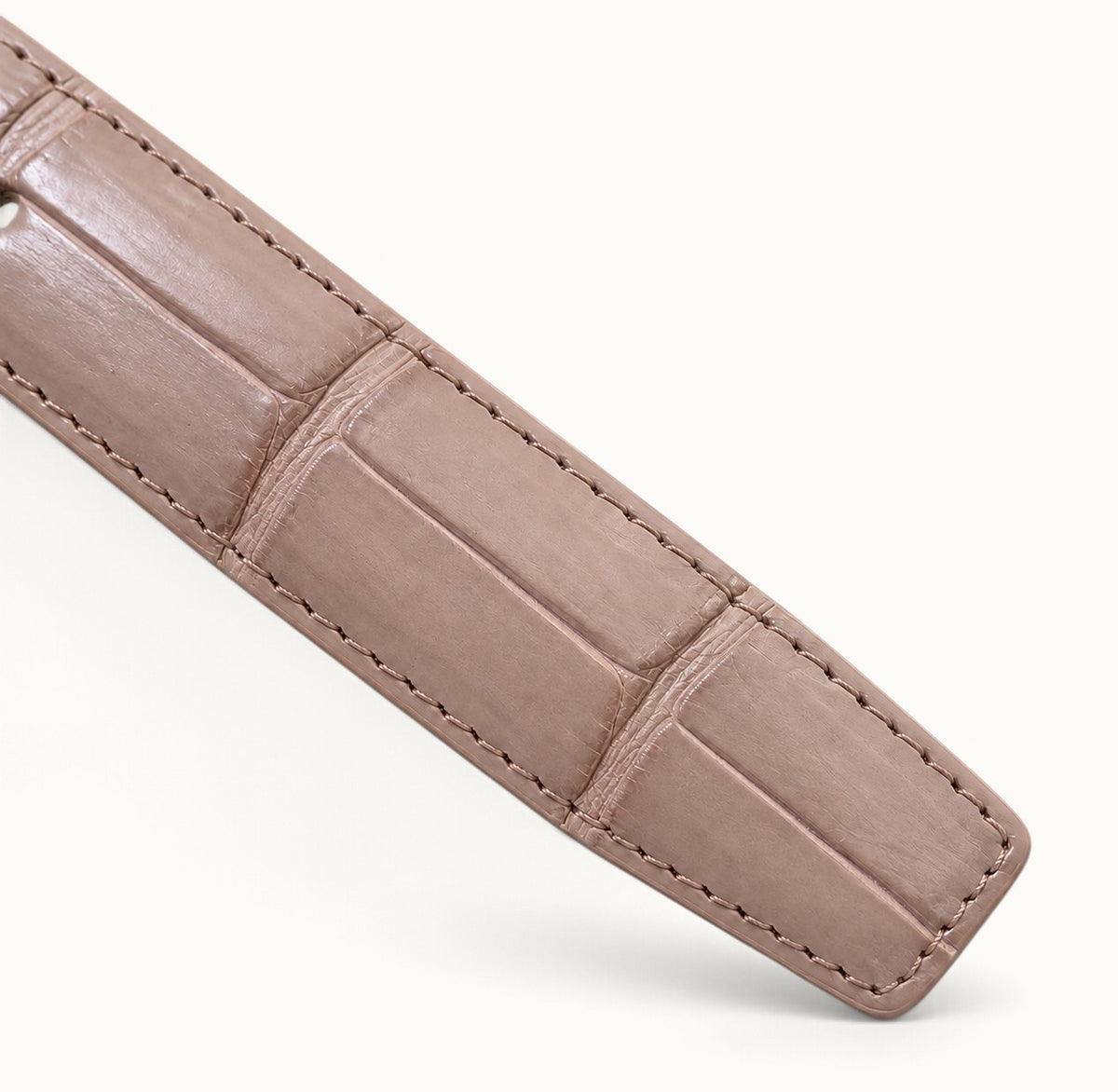 Blush pink crocodile belly leather belt tip with natural rectangular scales, rounded corners, and detailed edge stitching.