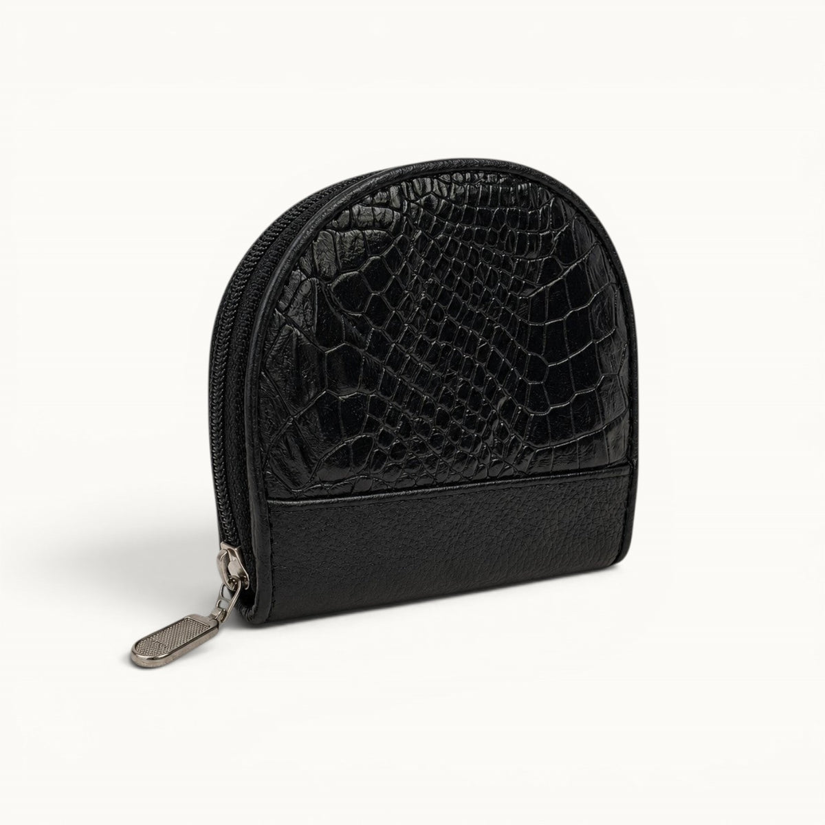 Angled view of The Sovereign black crocodile leather small zip pouch with a rounded silhouette, pebbled leather base, and silver-tone hardware.