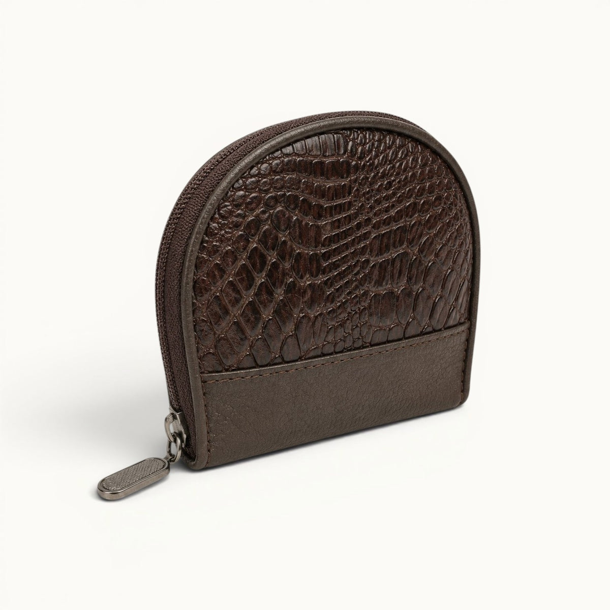 Angled view of The Sovereign brown crocodile leather coin case with a compact zip-around design, textured leather trim, and silver-tone pull.