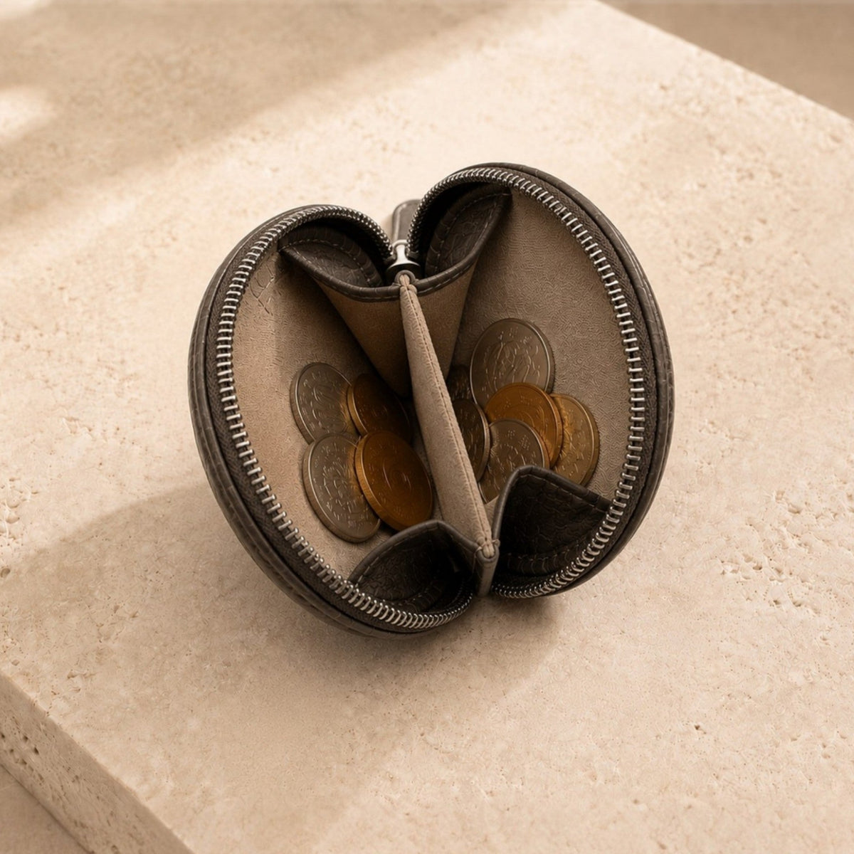 Open view of The Sovereign taupe green crocodile leather coin pouch filled with coins, showing its divided interior and secure zip-around closure.
