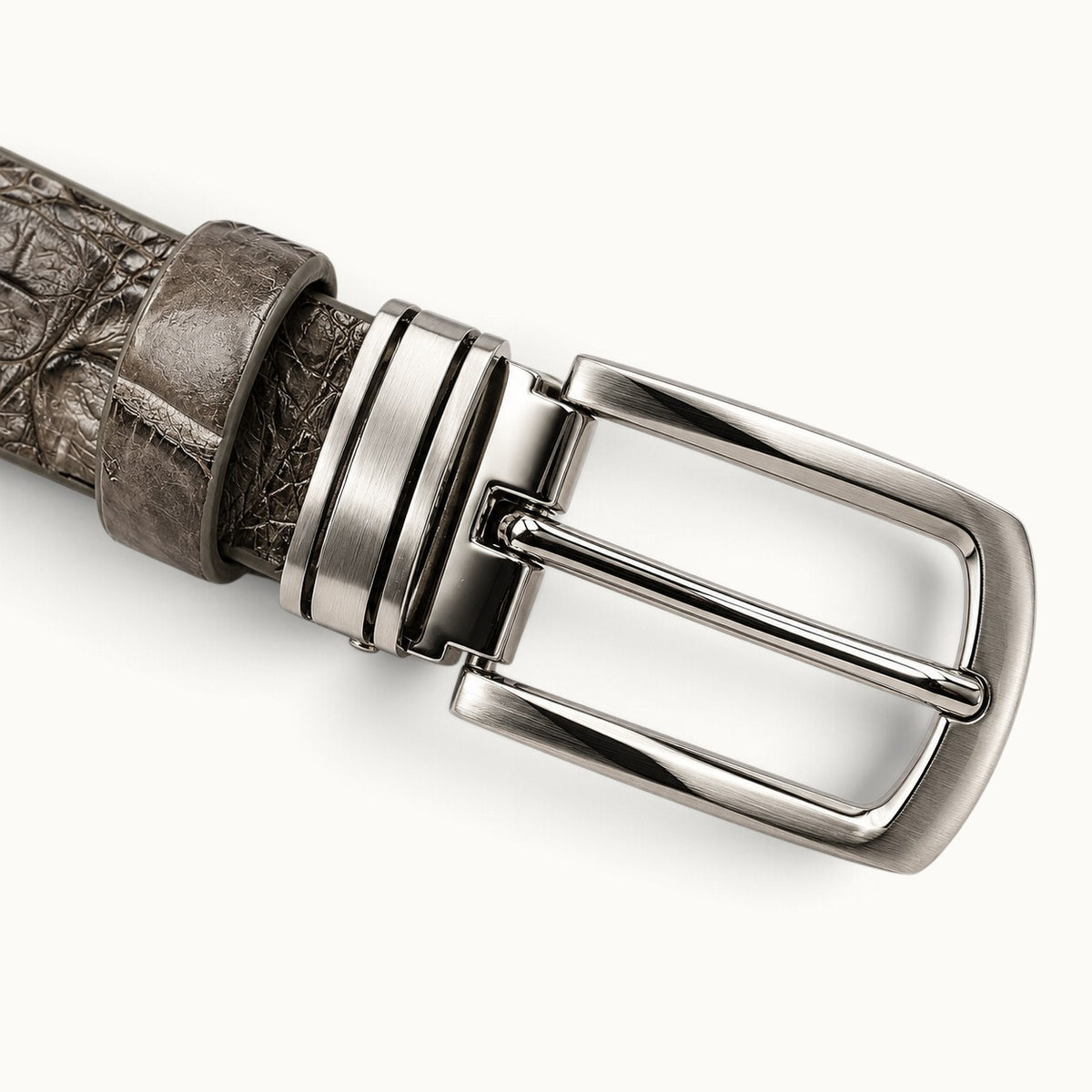 Close-up of The Waverly Crocodile Belt's removable solid brass buckle with brushed and polished silver-tone finish, metal keeper, and matching leather loop.