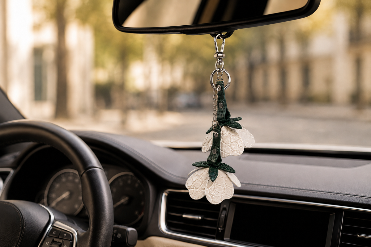 Stone Ivory Valencia crocodile flower charm hanging from the rear view mirror inside a luxury car