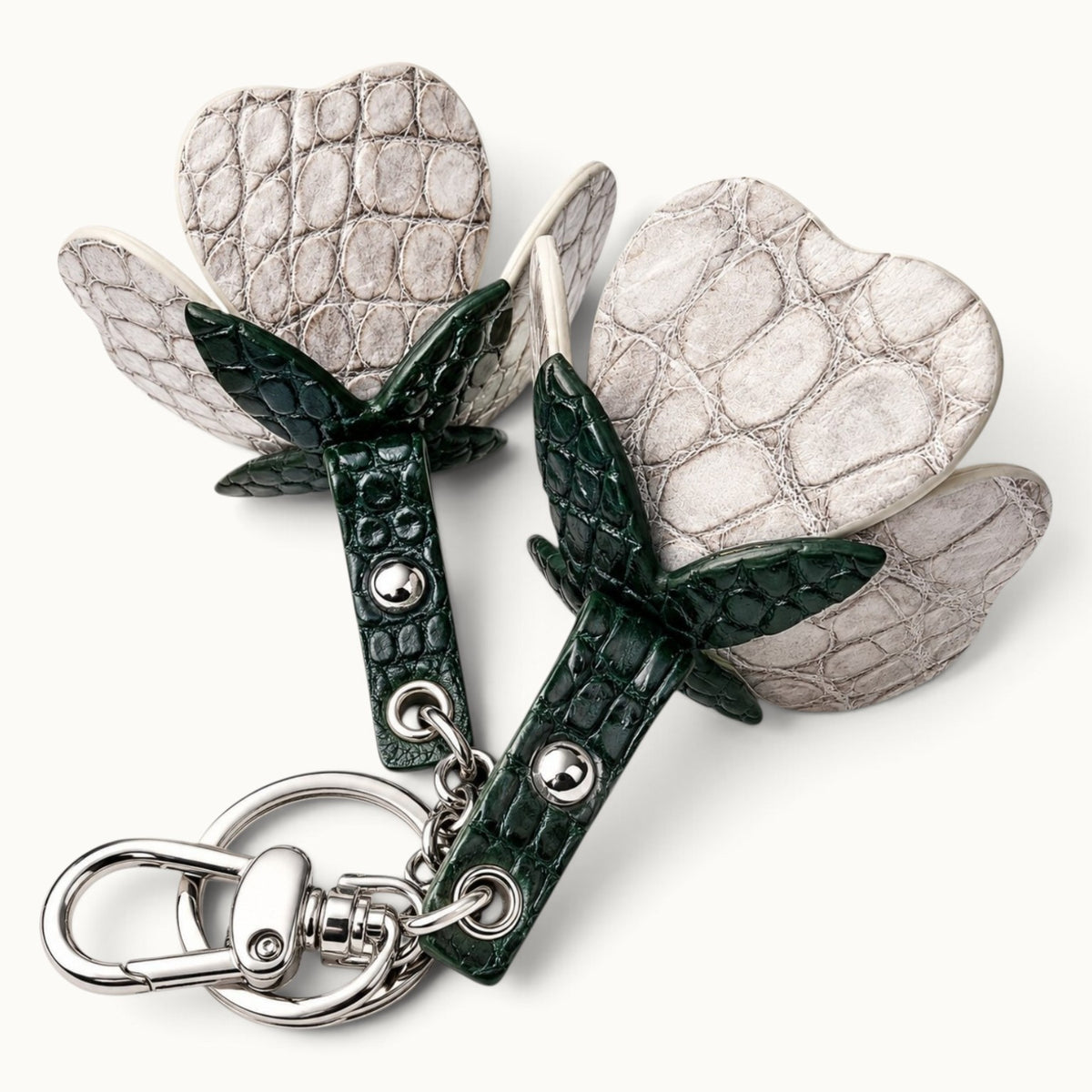 Close-up of Stone Ivory crocodile leather scales, dark green leaves, rivets, chain, and silver-tone hardware on The Valencia charm